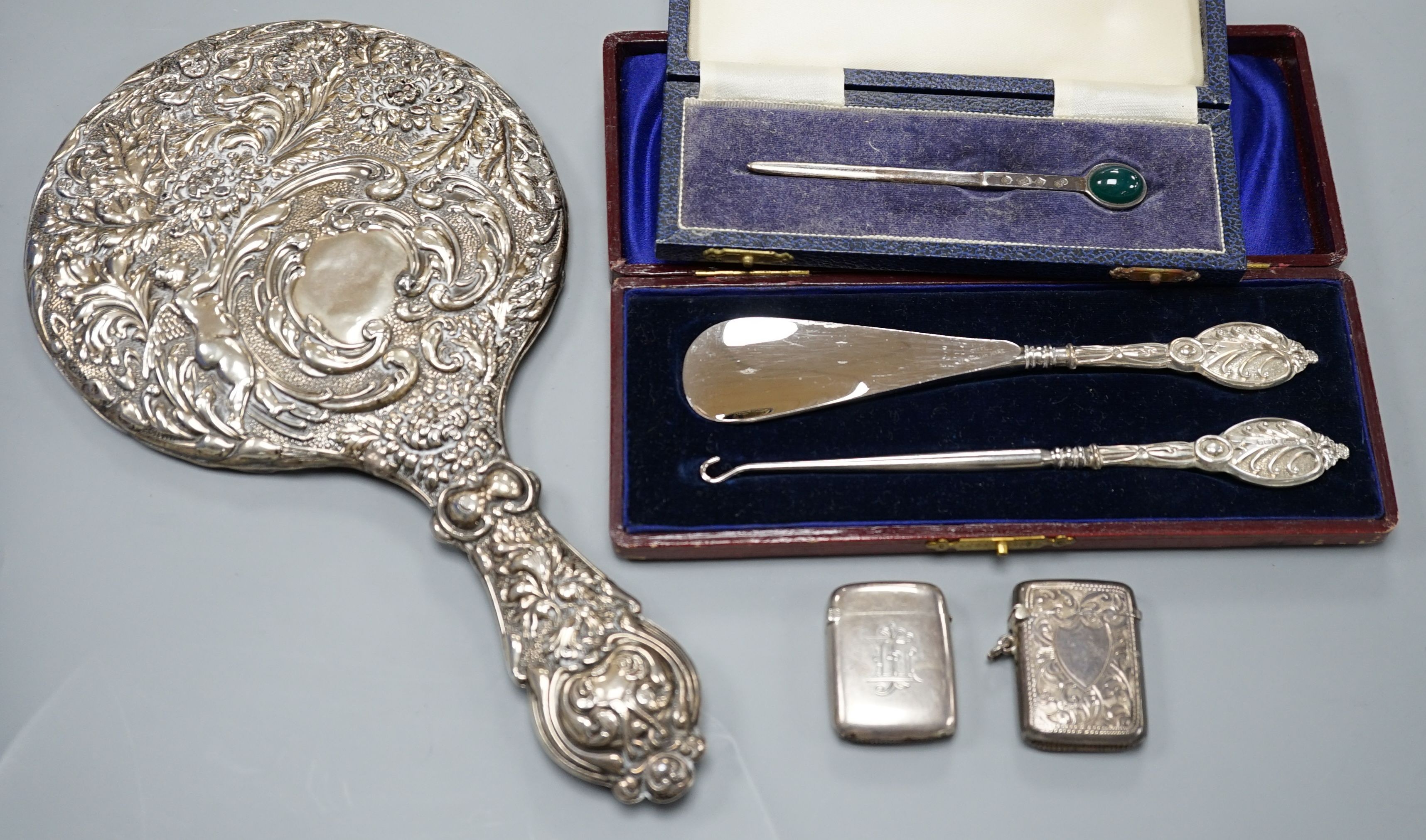 A group of small silver to include two vesta cases, a hand mirror, paste pin and a cased button hook and shoehorn.
